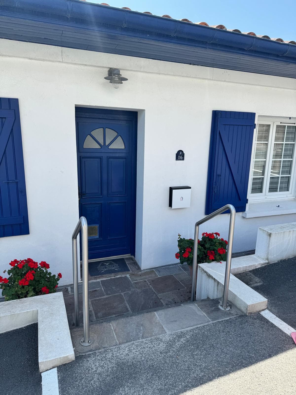 Vue 3/4 de la maison basque, porte bleue et plaque numérotée